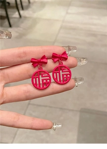 Macro detail of red festive bow earrings with hollowed out fortune character design