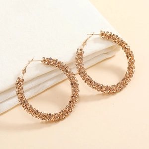 Detail view of large gold hoop earrings with sparkling champagne rhinestones on fabric