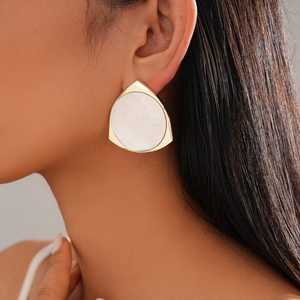 Close-up of a 14K gold plated triangle earring with a white round shell inlay on model