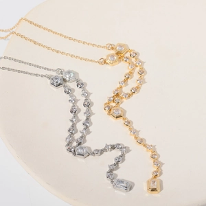 Detail of gold and silver Y-necklaces with sparkling zircon geometric pendants on a ceramic plate