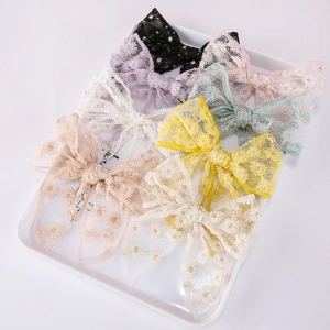Set of 8 colorful embroidered mesh flower bow hair clips for girls displayed on a tray