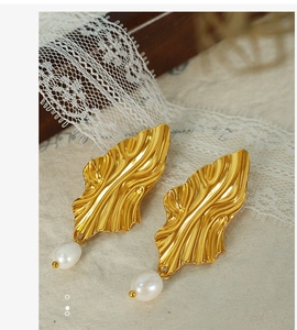 Detail of gold leaf earrings with wavy texture and white freshwater pearl pendants