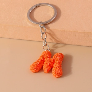 Detailed view of orange rose petal texture on M-shaped keychain with silver metal ring