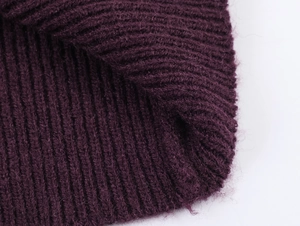Gros plan sur un tricot violet foncé avec texture côtelée et détails de fibres de laine