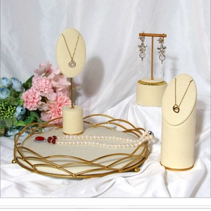 Elegant gold metal jewelry display set with beige velvet lining on white satin background