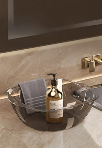 Detail of grey transparent thickened PET basin on bathroom counter with golden fixtures
