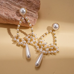 Macro detail of vintage baroque teardrop pearl earrings with gold bead accents on wood