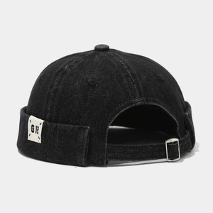 Detail of black denim skull cap featuring adjustable metal buckle and woven GR brand tag