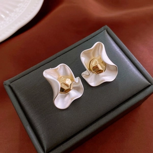 French style white wavy flower stud earrings with a gold center on a jewelry box