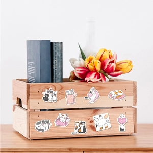 Detailed view of nine cartoon cat stickers on a wooden box with tulips in the background