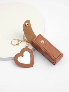 Detail view of brown PU leather lipstick case and heart mirror keychain with gold hardware