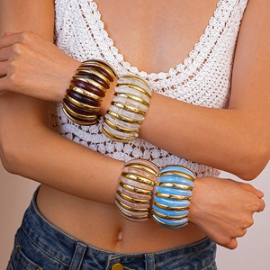Close-up of colorful marbled acrylic beaded bracelets with gold accents on model