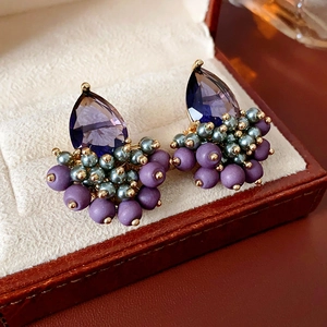 Macro shot of purple teardrop earrings with beaded details in a vintage jewelry box