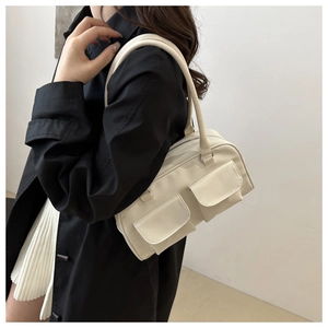 Elegante borsa a tracolla beige con due tasche frontali indossata da una modella chic