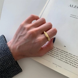 Close-up of a minimalist gold irregular 925 silver ring worn over an open magazine