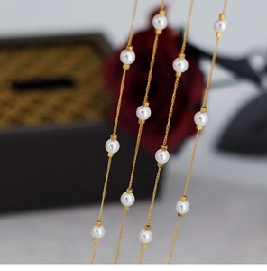 Macro detail of elegant golden chain necklace with round white pearls on rose background