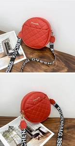 Detail view of the red round quilted PU leather crossbody bag with lettered wide strap