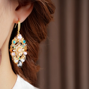 Macro detail of vintage gold drop earring featuring colorful crystals on a model's ear