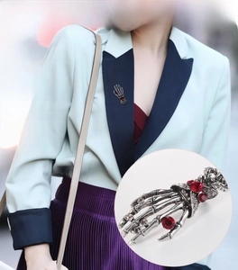 Close-up of retro silver skeleton hand brooch with red rhinestones in punk gothic style