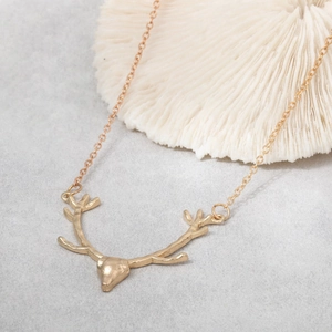 Detailed view of a 3D golden reindeer antler pendant with a delicate fine chain necklace