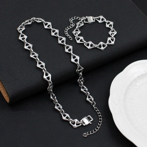 Silver steel jewelry set with geometric link necklace and bracelet on a black book