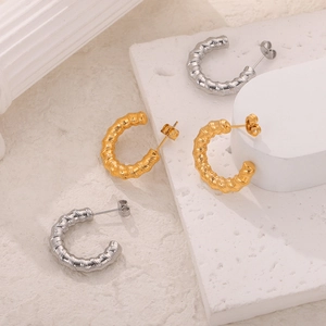 Minimalist gold and silver C-shaped spiral texture earrings on elegant stone display