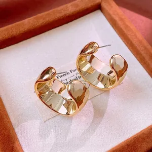 Minimalist wide C-shape gold-plated hoop earrings with a textured hammered finish in a box