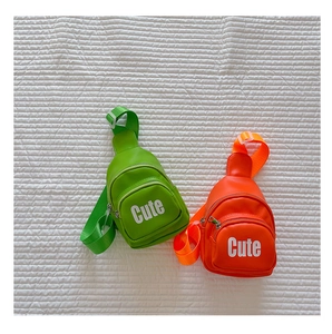 Detail view of bright green and orange mini chest bags with Cute lettering on white quilt