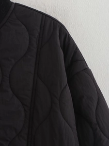Close-up of black quilted jacket featuring ribbed collar and wavy stitching detail