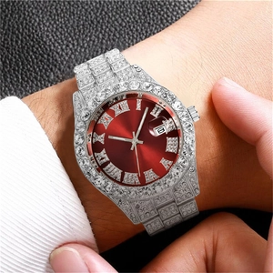 Close-up of a silver iced-out quartz watch with a red Roman numeral dial on a wrist