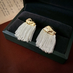 Detailed macro view of gold hammered studs with long silver chain tassels in jewelry box