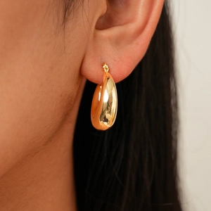 Close-up of a polished golden metallic hoop earring worn on a model for a chic look