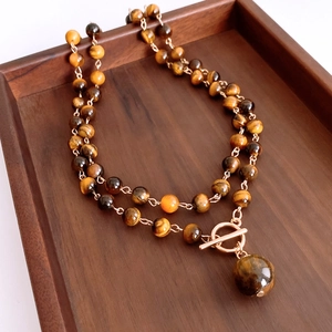 Detail of tiger eye bead necklace with gold OT buckle on a vintage wooden tray