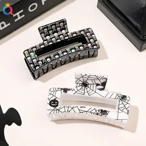 Detail of Halloween hair claws featuring holographic skulls and black spider web patterns