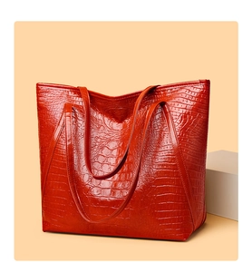 Detailed close-up of vibrant red crocodile pattern tote bag with polished texture