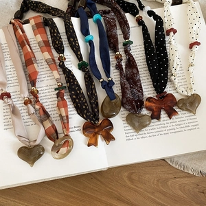 Detailed flat lay of fabric heart necklaces with various patterns on vintage book pages