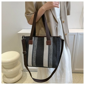 Detail of the striped canvas tote bag with brown leather handles and adjustable strap