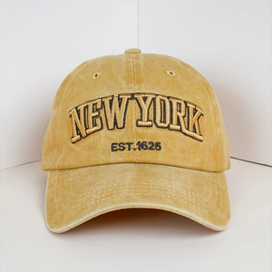 Close-up of mustard yellow baseball cap with New York embroidery and distressed brim detail