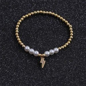 Detail of gold beaded bracelet with white pearls and a micro-pave zircon lightning charm