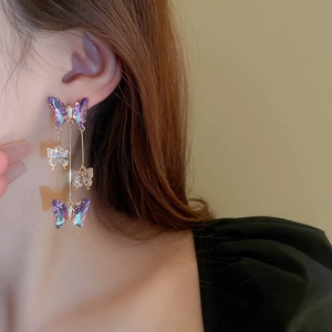 Detail of purple butterfly earrings with sparkling crystals and long gold tassels
