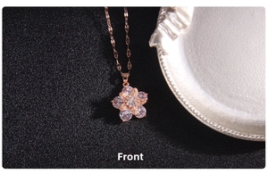 Close-up of rose gold four-leaf clover pendant with spinning zircon stones on cross chain