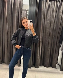 Selfie miroir d'un blouson aviateur matelassé noir pour femme avec un jean bleu taille haute