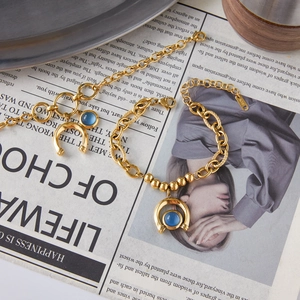 Detail of gold horseshoe bracelet with blue resin bead and K18 engraving on vintage paper