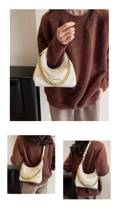 Detail of white quilted underarm bag with gold chain strap shown on a model