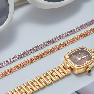 Détails d'une montre carrée dorée avec bracelets en strass roses et lunettes de soleil blanches