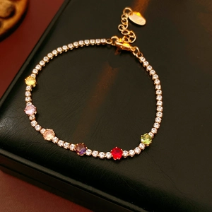 Detail of a vintage gold bracelet with vibrant round colorful zircons and heart pendant