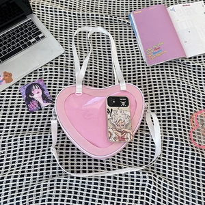 Detail of pink heart-shaped ita bag with clear window and adjustable straps on a grid mat
