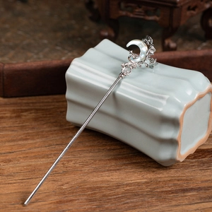 Detailed shot of a silver hair pin featuring a mother-of-pearl crescent moon and stars