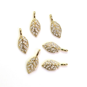Pendentif en forme de feuille dorée avec pavé de zircons sur un fond blanc pur