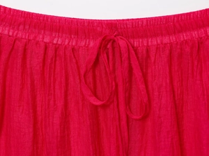 Détail de la jupe midi plissée rouge avec taille élastique à cordon et tissu texturé